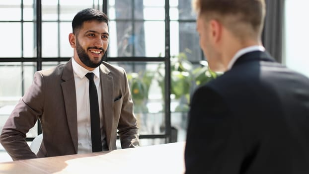 Businessmen shaking hands at the board room table.