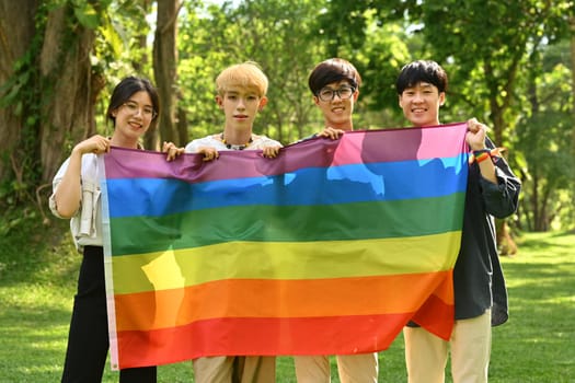 Group of young people holding pride rainbow flag, supporting LGBTQ community and equality social.