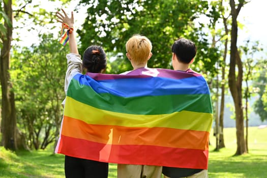 Group of young people holding pride rainbow flag, supporting LGBTQ community and equality social.