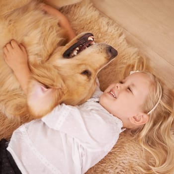 Dog, girl and hug together on floor in living room and golden retriever, kid and playing with pet on lounge carpet. Young child, labrador and happiness or family home, pets and children from above.