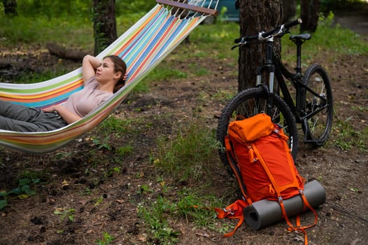 Caucasian woman lies in a hammock in a pine forest.