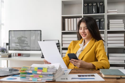 Smiling young business woman, happy beautiful professional lady worker holding smartphone using cellphone mobile working at office checking cell phone at workplace.