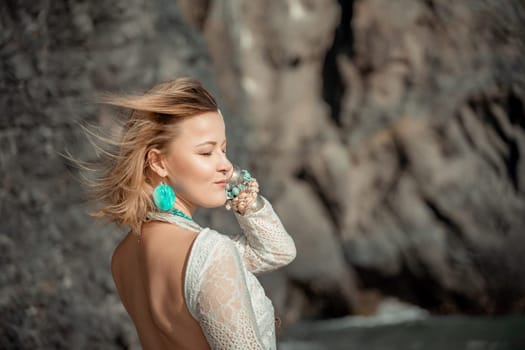 Middle aged woman looks good with blond hair, boho style in white long dress on the beach decorations on her neck and arms