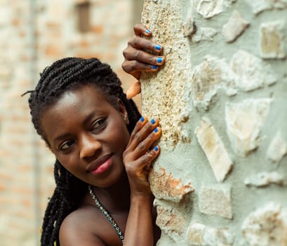 relaxed young black woman sitting. Stylish model. Braid dreadlock hairstyle. Confident African female in selective focus outdoors, fashion style, happiness concept. Outdoors.