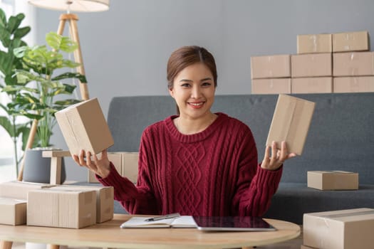 Happy young asian woman startup small business freelance holding parcel box and computer laptop, Online marketing packing box delivery concept.