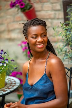 relaxed young black woman sitting. Stylish model. Braid dreadlock hairstyle. Confident African female in selective focus outdoors, fashion style, happiness concept. Outdoors.