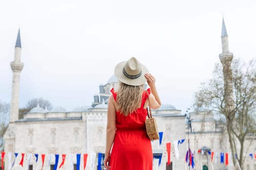 A beautiful travel blogger girl in a long red dress and a straw hat is photographed at the ancient sights in Istanbul in Turkey.