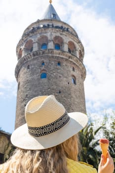 Beautiful young tourist girl in fashionable clothes poses with view of landmark Galata tower in Beyoglu,Istanbul,Turkey.Traveler Concept image.