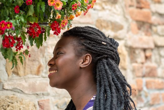 relaxed young black woman sitting. Stylish model. Braid dreadlock hairstyle. Confident African female in selective focus outdoors, fashion style, happiness concept. Outdoors.