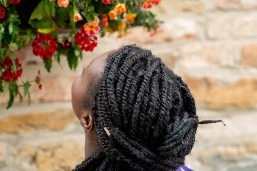 relaxed young black woman sitting. Stylish model. Braid dreadlock hairstyle. Confident African female in selective focus outdoors, fashion style, happiness concept. Outdoors.