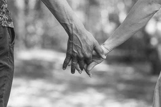 The husband's hand firmly holds the wife's hand close-up. Loving couple walking and holding hands. Reliable and strong marriage. The concept of romance, fidelity in marriage and love. Black and white