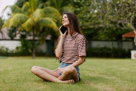 lifestyle woman seasonal tree blogger smiling person shirt palm caucasian network girl using smile spring phone happy grass park nature outdoor striped