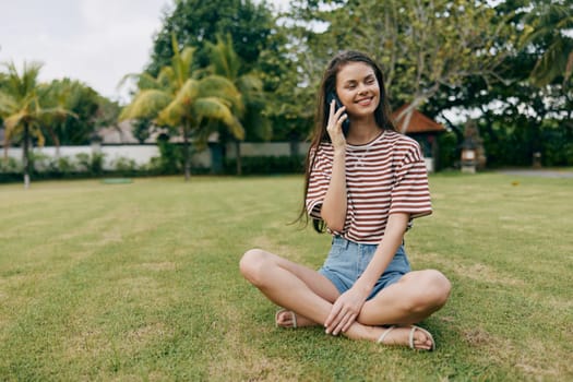 woman call application tree walk lifestyle spring young beautiful park smile striped app blogger girl happy smiling nature palm phone grass outside