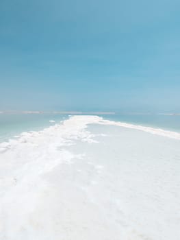 Landscape view on Dead Sea salt crystals formations, clear cyan green calm water at Ein Bokek beach, Israel