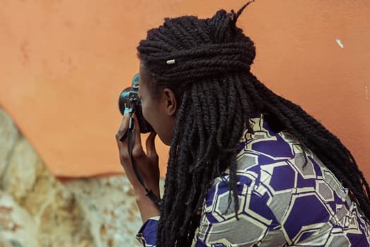 Close up portrait of beautiful young woman with braid hairstyle concentrated while making a photograph with reflex camera over a wall outdoors