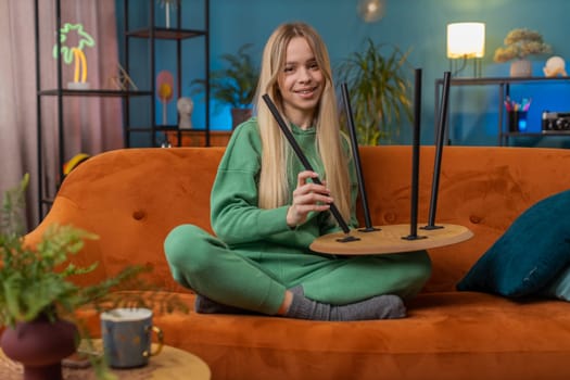 Happy woman finishing assembling furniture at home. Successful table desk collect, repair, fixing. Teen girl after moving into new apartment. Advertisement of a furniture store. Mortgage, lifestyle