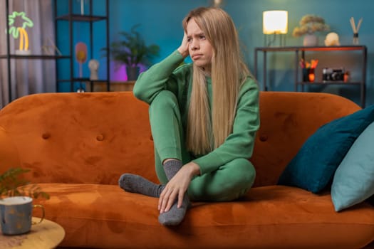 Sad lonely woman sits at home room looks pensive thinks over life concerns or unrequited love suffers from unfair situation. Alone teen girl problem, break up, depressed feeling bad annoyed burnout