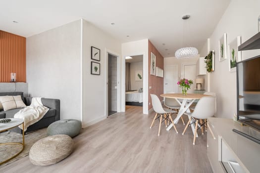 Comfortable seating area with a terracotta color wall with a sofa and poufs near the dining area in the living room studio. Concept of a modern European interior.