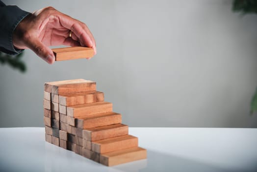 Business hand arranging put wooden block stacking step stair growth success process, financial risk management and strategic plan and business challenge planning concept, prevent collapse or crash