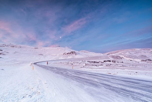 Hverir iced road in winter at sunrise and moon in the sky, Iceland