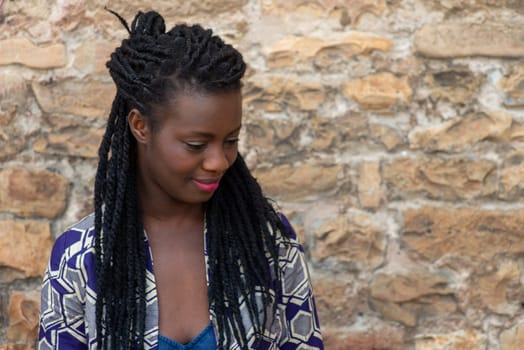 relaxed young black woman sitting. Stylish model. Braid dreadlock hairstyle. Confident African female in selective focus outdoors, fashion style, happiness concept. Outdoors.