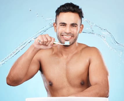 Teeth, dental care and water splash, man with toothbrush and toothpaste on blue background with smile on face. Morning routine, healthcare and fresh studio portrait of model in India brushing teeth