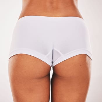 Buttocks, underwear and closeup with a model black woman in studio on a gray background from the back. Skin, real and bum in panties with a normal female posing to promote natural body positivity.