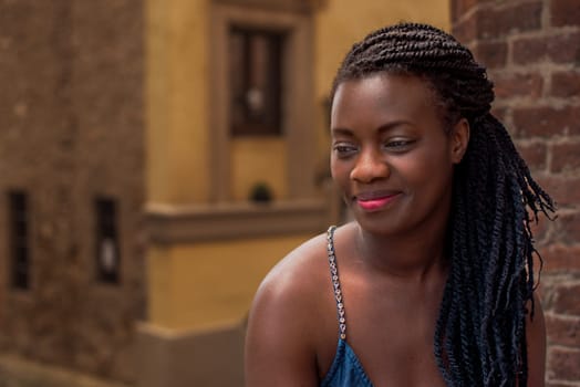 relaxed young black woman sitting. Stylish model. Braid dreadlock hairstyle. Confident African female in selective focus outdoors, fashion style, happiness concept. Outdoors.