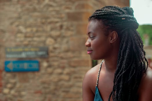 relaxed young black woman sitting. Stylish model. Braid dreadlock hairstyle. Confident African female in selective focus outdoors, fashion style, happiness concept. Outdoors.