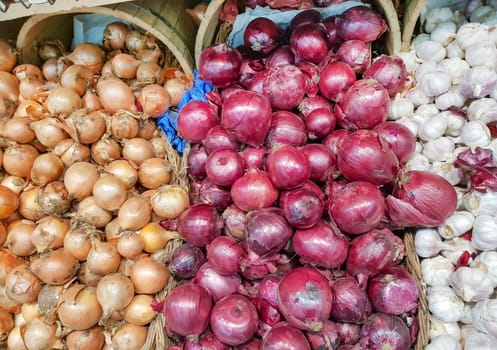 Close-up view of the counter in the vegetable market, sale of onions and garlic of different varieties.