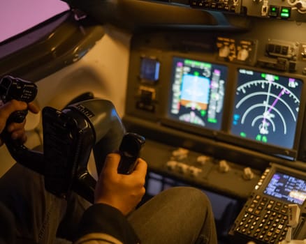 A man is studying to be a pilot in a flight simulator. Close-up of male hands navigating an aircraft