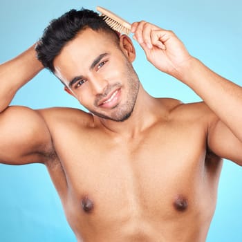 Beauty, hair and brush with portrait of man for grooming, hygiene or self care routine. Salon, hairstyle and treatment with model for cosmetics, brushing and product against blue background in studio.