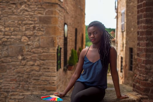 relaxed young black woman sitting. Stylish model. Braid dreadlock hairstyle. Confident African female in selective focus outdoors, fashion style, happiness concept. Outdoors.