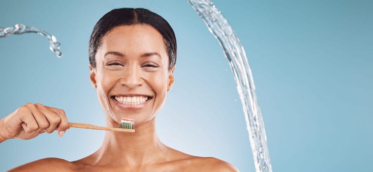 Black woman, toothbrush and brushing teeth with a water splash and toothpaste on blue studio background for dental health and wellness. Portrait and face of model cleaning mouth with eco brush.