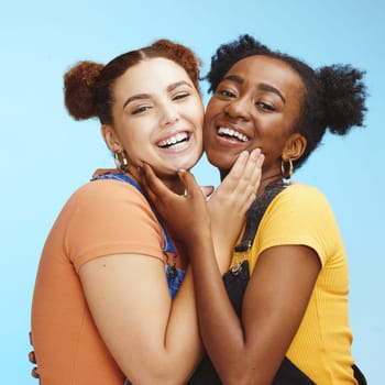 Friends, hug and portrait smile for happy friendship, lesbian or relationship against a blue studio background. Face of interracial female couple smiling and touching in pride for LGBTQ and fashion.