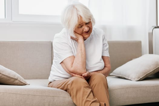 Elderly woman severe neck pain sitting on the sofa, health problems in old age, poor quality of life. High quality photo