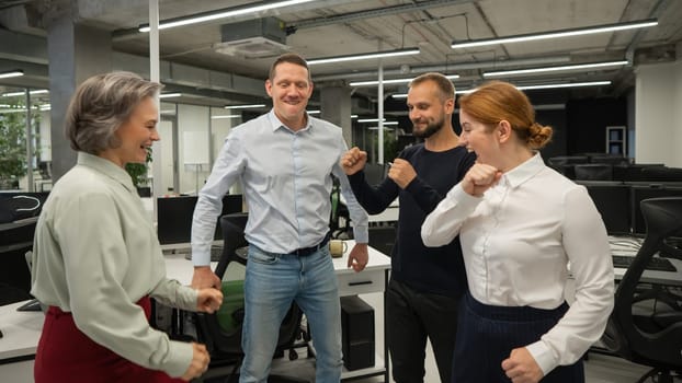 Four colleagues give the low five in the office
