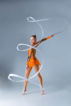 beautiful Caucasian girl gymnast with white ribbon on a blue background