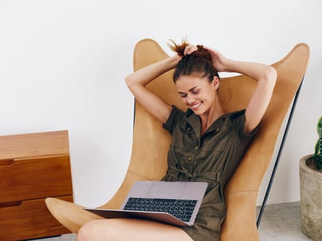 Woman sitting on a chair with a laptop at home beautiful smile and relaxation, modern stylish interior Scandinavian lifestyle, copy space. High quality photo