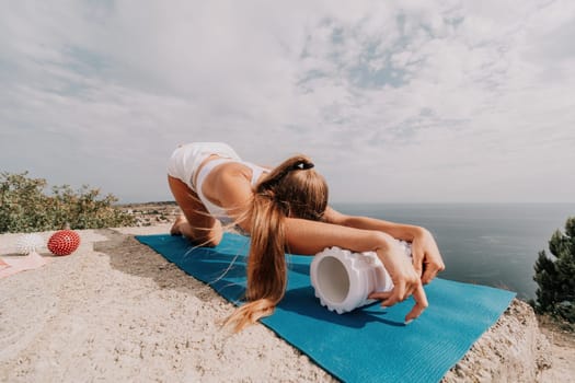 Woman sea pilates. Sporty, middle-aged woman practicing pilates in park near the sea. trains on a yoga mat and exudes a happy and active demeanor, promoting the idea of a healthy lifestyle through exercise and meditation.