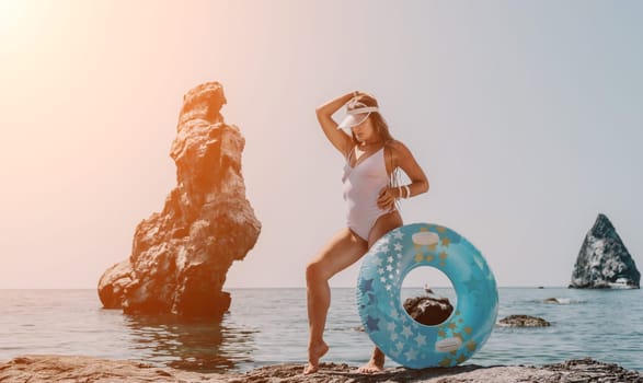 Woman summer sea. Happy woman swimming with inflatable donut on the beach in summer sunny day, surrounded by volcanic mountains. Summer vacation concept