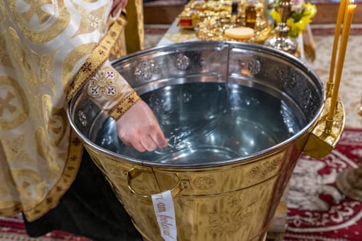 baptismal font with water for the Orthodox baptism in the church, with the priest