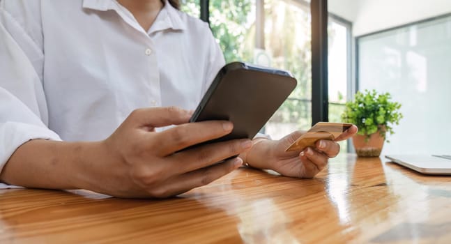 Close up woman holding smartphone and banking credit card, involved in online mobile shopping at home, happy female shopper purchasing goods or services in internet store.