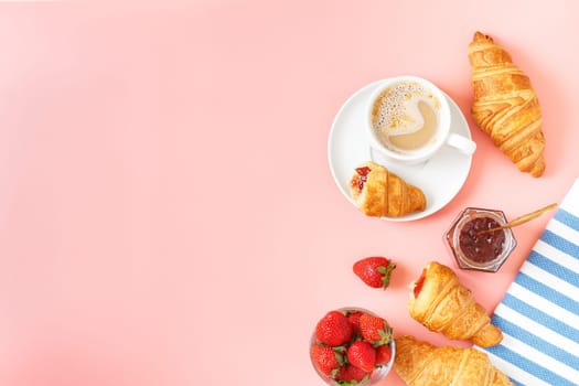 Delicious breakfast with fresh croissants, coffee, berry jam and fresh berries on a pink background. copy space.