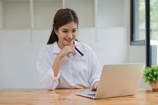 Young woman holding credit card and using laptop computer. Online shopping concept.