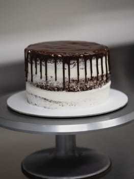 pastry chef preparing a chocolate frosted dripped icing cup cake with sweet fruit topping and golden brush strokes