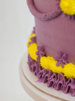 frosted icing violet yellow classic cilyndrical cake with text messagge topping on studio white background. Romantic layered cupcake.