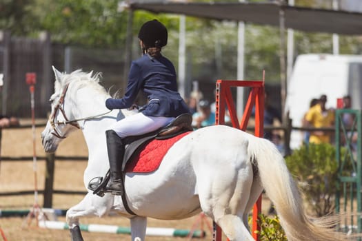 Equestrian sport - a teenage girl in uniform riding a horse at the ranch. Mid shot