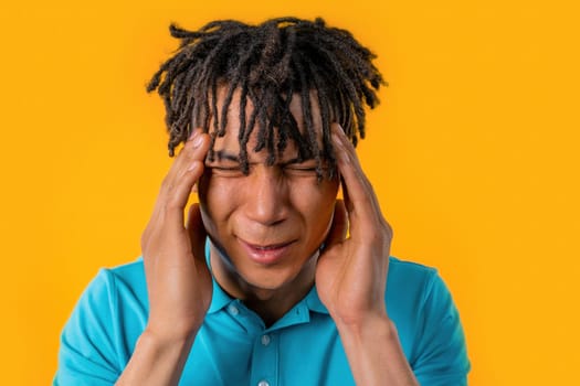 Young man having headache, studio portrait. Guy putting hands on head, isolated on violet background. Concept of problems, medicine, illness