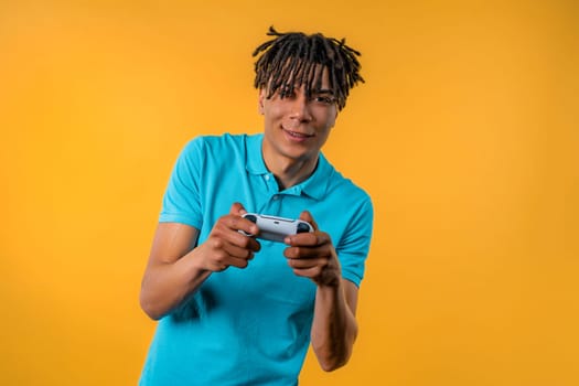 Handsome young man playing video exciting game on Tv with joystick isolated on yellow studio background. Using modern technology.